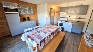 A compact kitchen with a dining table, wooden cabinets, and a built-in oven.