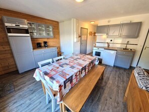 Una cocina compacta con mesa de comedor, armarios de madera y horno empotrado.