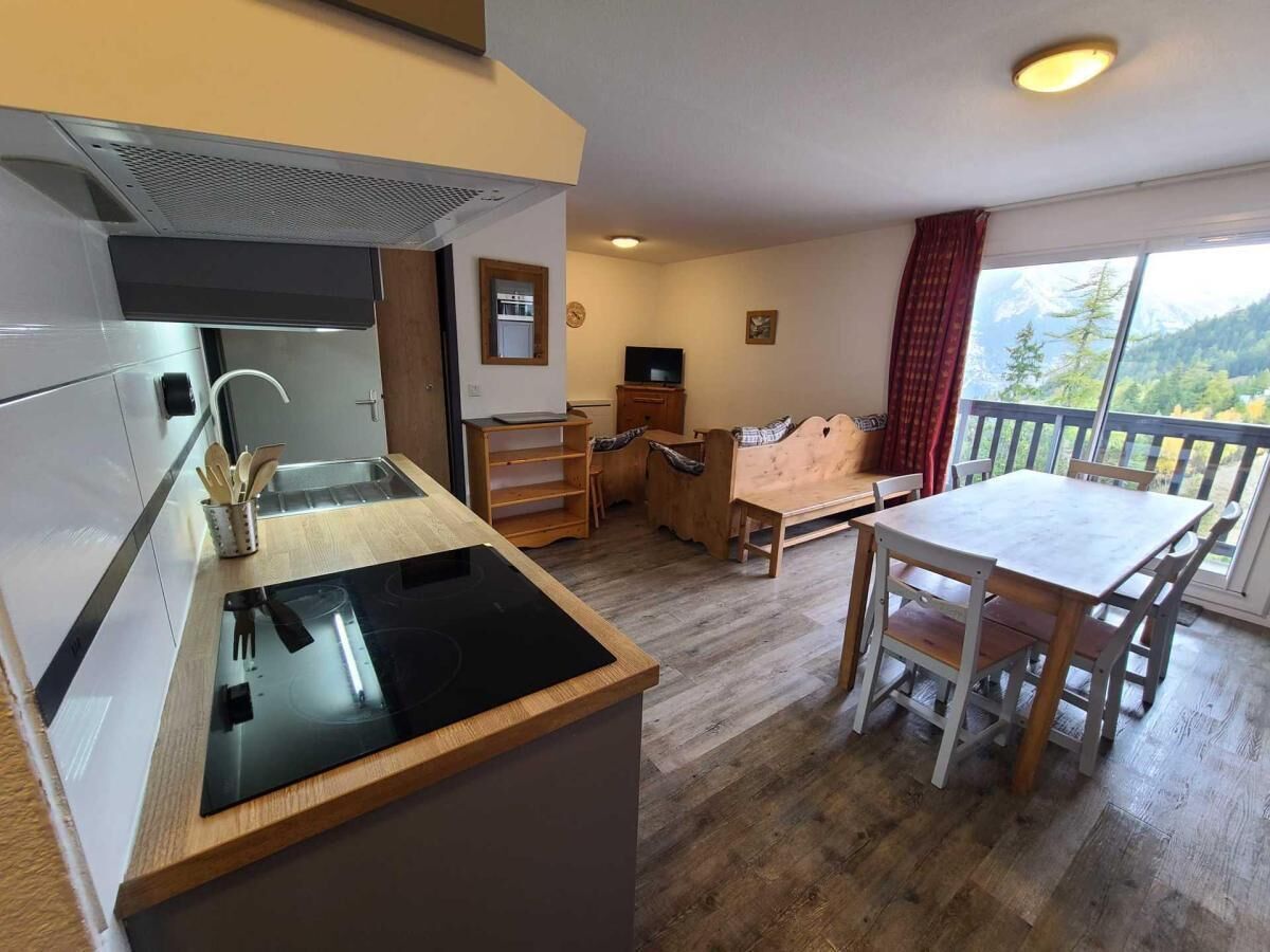 A compact kitchen with a stove, sink, and wooden dining table with chairs.