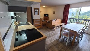 A compact kitchen with a stove, sink, and wooden dining table with chairs.