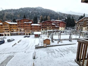 Un estacionamiento cubierto de nieve con varios edificios de madera, incluyendo un telesilla y una pequeña construcción de madera.