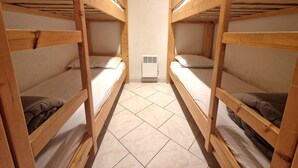 A room with two bunk beds, a small heater, and a tiled floor.
