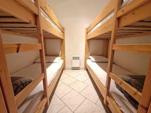 Una habitación con dos literas, un calentador pequeño y piso de baldosas.