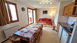 A compact kitchen with a dining table, wooden chairs, a red sofa, and a small sink. - 100m from ski slopes, 1st floor, balcony, ski locker, 48m², Valfréjus (Valfréjus)