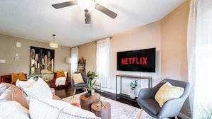 A modern living room with a sofa, armchairs, a coffee table, and a TV mounted on the wall. - Chic 6BDRM Getaway - KingBed - Patio - BBQ - Garage - Wifi (Edmonton)