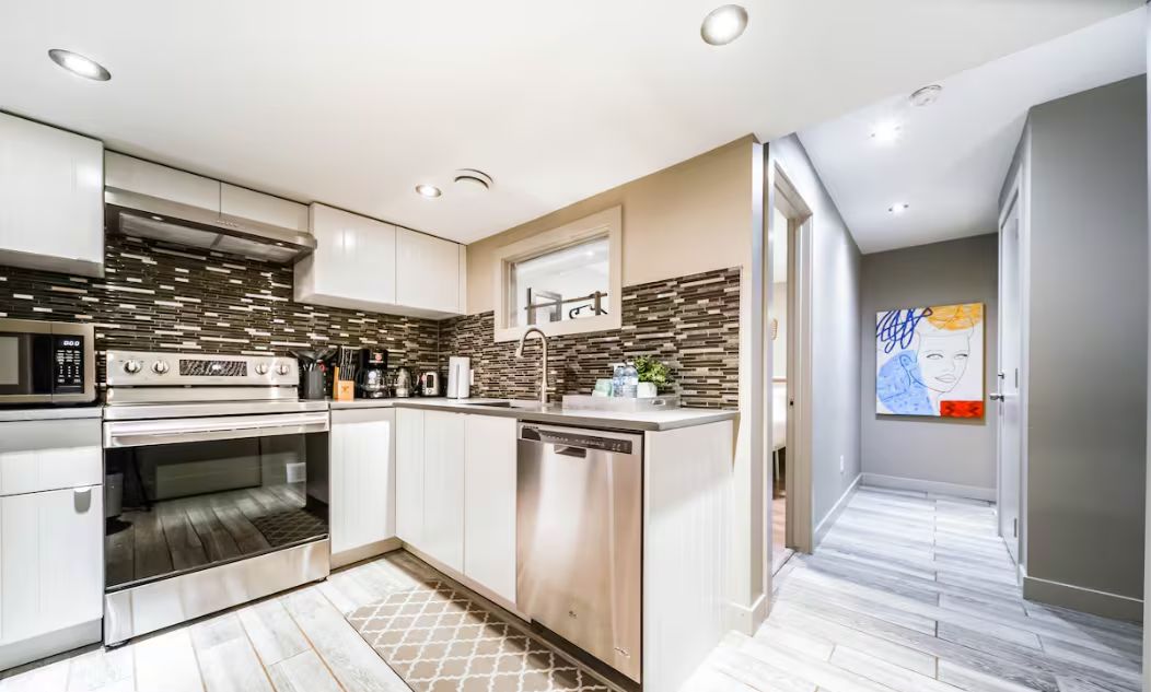 A modern kitchen with stainless steel appliances, a dishwasher, and a tiled backsplash.