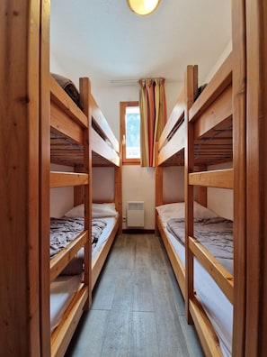 A narrow room with bunk beds, a small window with curtains, and a ceiling light. - Resort center, 1st floor, view open, balcony, tv, ski locker, 42m², Valfréjus (Valfréjus)