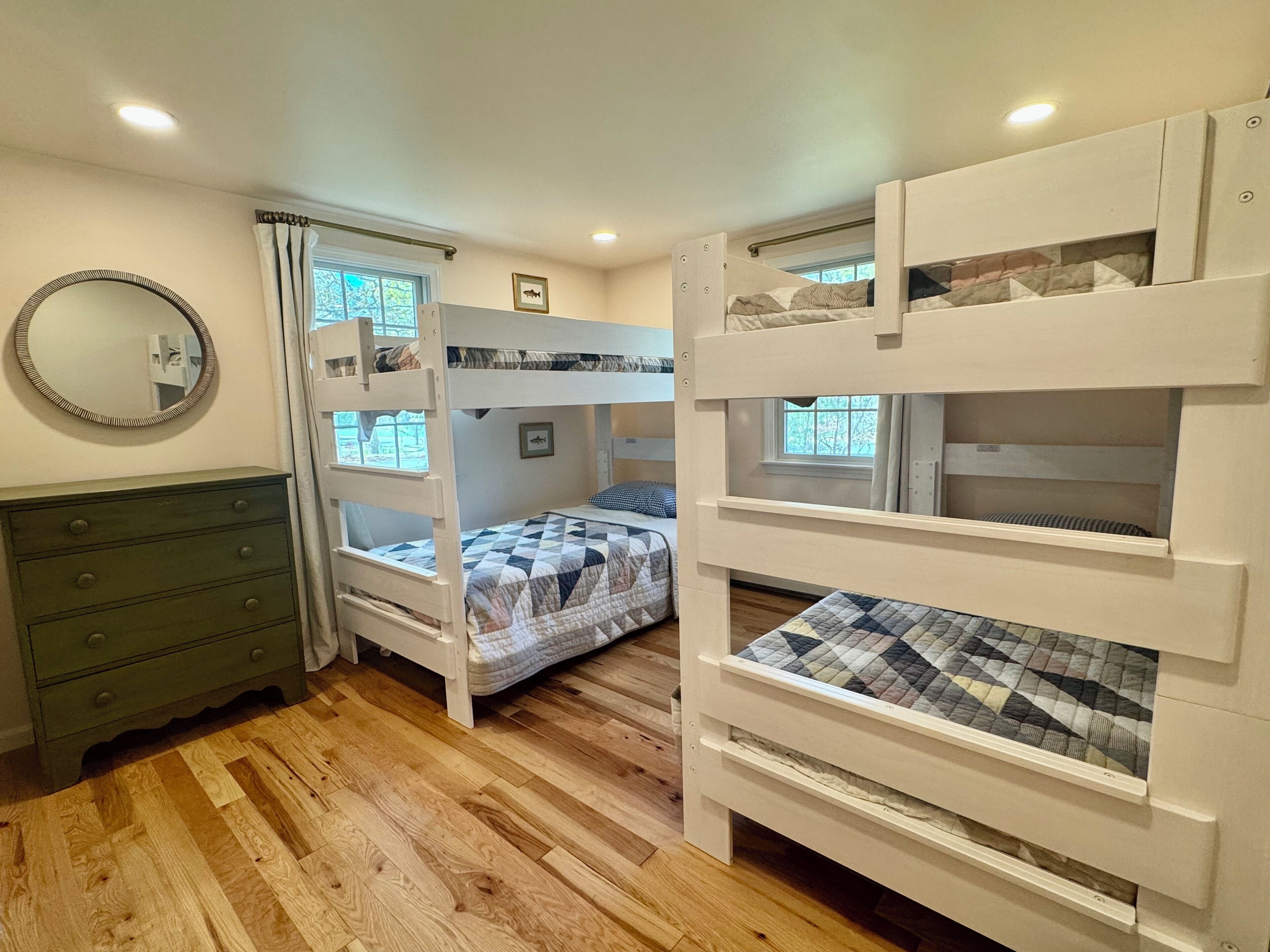 Habitación con literas, cómoda, espejo y ventana con cortinas.
