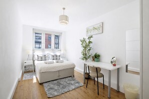 A modern bedroom with a bed, bedside tables, a desk, and a chair.