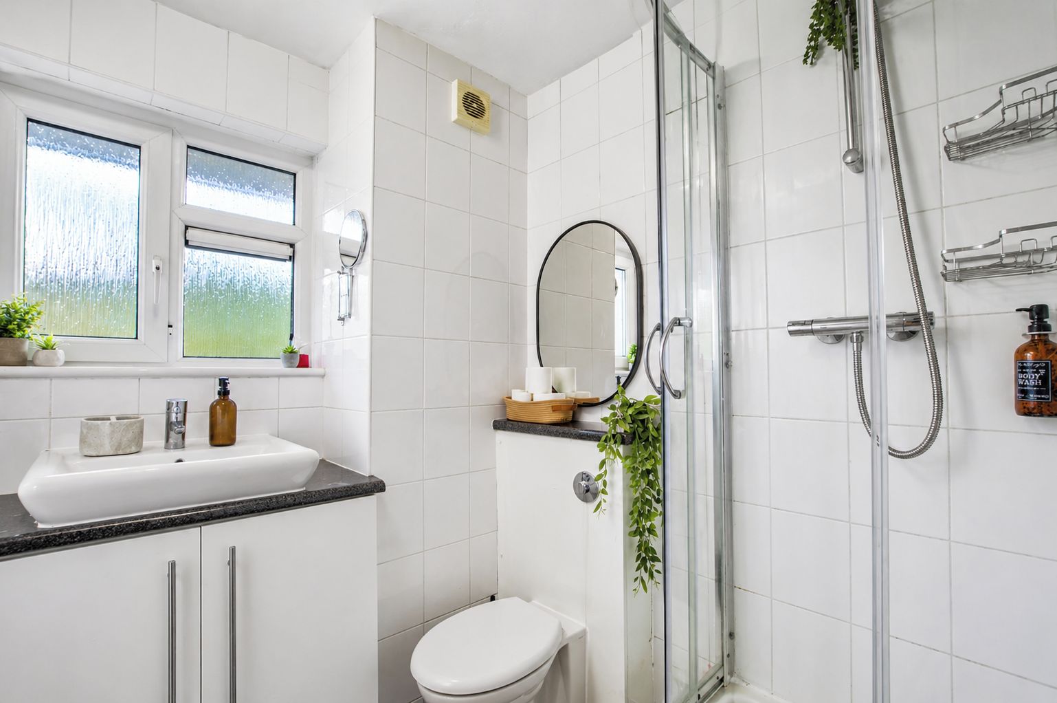 Een moderne badkamer met douche, toilet en wastafel.