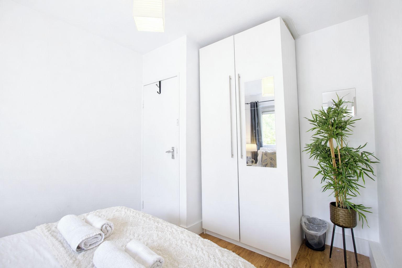 Une chambre à coucher avec un lit, une armoire blanche et une plante en pot.