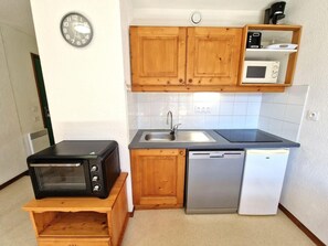 Una cocina compacta con muebles de madera, microondas, tostadora y lavavajillas.