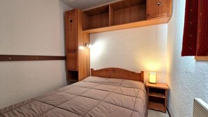 Une chambre à coucher avec un lit, une tête de lit en bois, des étagères intégrées et une lampe de chevet.