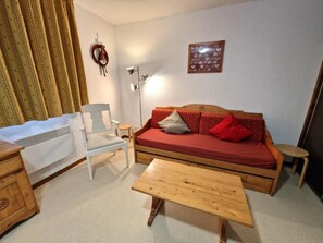 A cozy living room with a wooden sofa, a white chair, a small table, and a heater. - 100m from ski slopes, 2nd floor, balcony, ski locker, 36m², Valfréjus (Valfréjus)