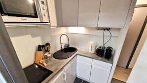 A compact kitchen with a microwave, sink, and countertop.
