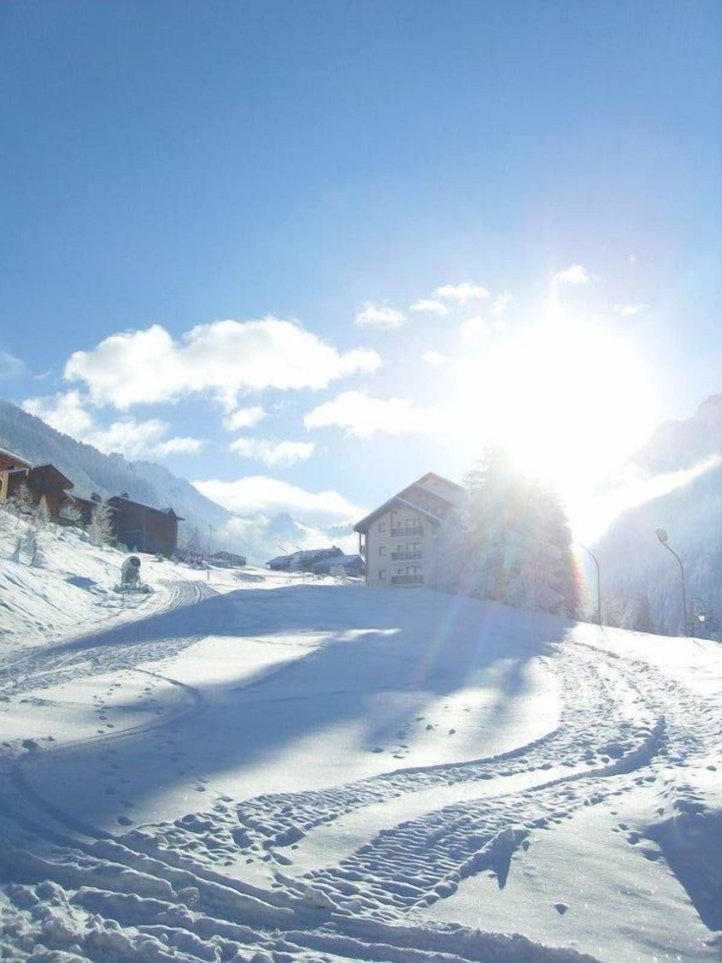 A snow-covered ski slope with a building in the background.