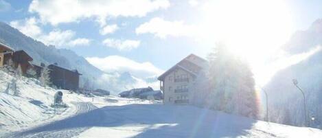 A snow-covered ski slope with a building in the background.