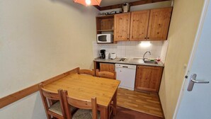 Uma cozinha compacta com armários de madeira, micro-ondas, lava-louças e uma mesa de jantar com cadeiras.