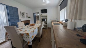 A dining area with a table set for four, a kitchen with a microwave, and a large window with curtains.