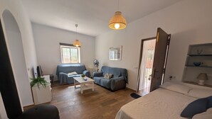A compact living space with a sofa, a bed, a small table, and a ceiling light.