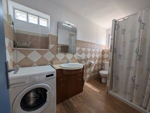 Un bagno funzionale con lavatrice, lavabo, specchio e WC.