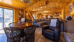 Un intérieur en bois comprenant une table à manger, des chaises, un canapé et une cheminée.