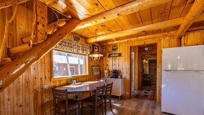 L’intérieur d’une cabane en bois comprend un coin repas, une cuisine et un réfrigérateur.