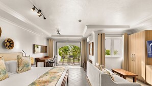 Ein Hotelzimmer mit Bett, Sofa, Esstisch und Blick ins Freie.