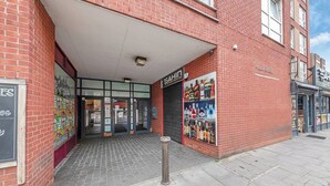 Edifício de tijolos com fachada que apresenta uma placa com o nome 'SAHIN' e uma vitrine com bebidas alcoólicas.