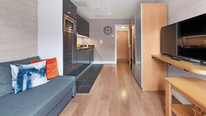 Uma sala de estar moderna com um sofá cinzento, uma TV de tela plana e um móvel de madeira para televisão.