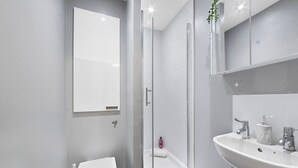 Uma casa de banho moderna com sanita, chuveiro e lavatório.