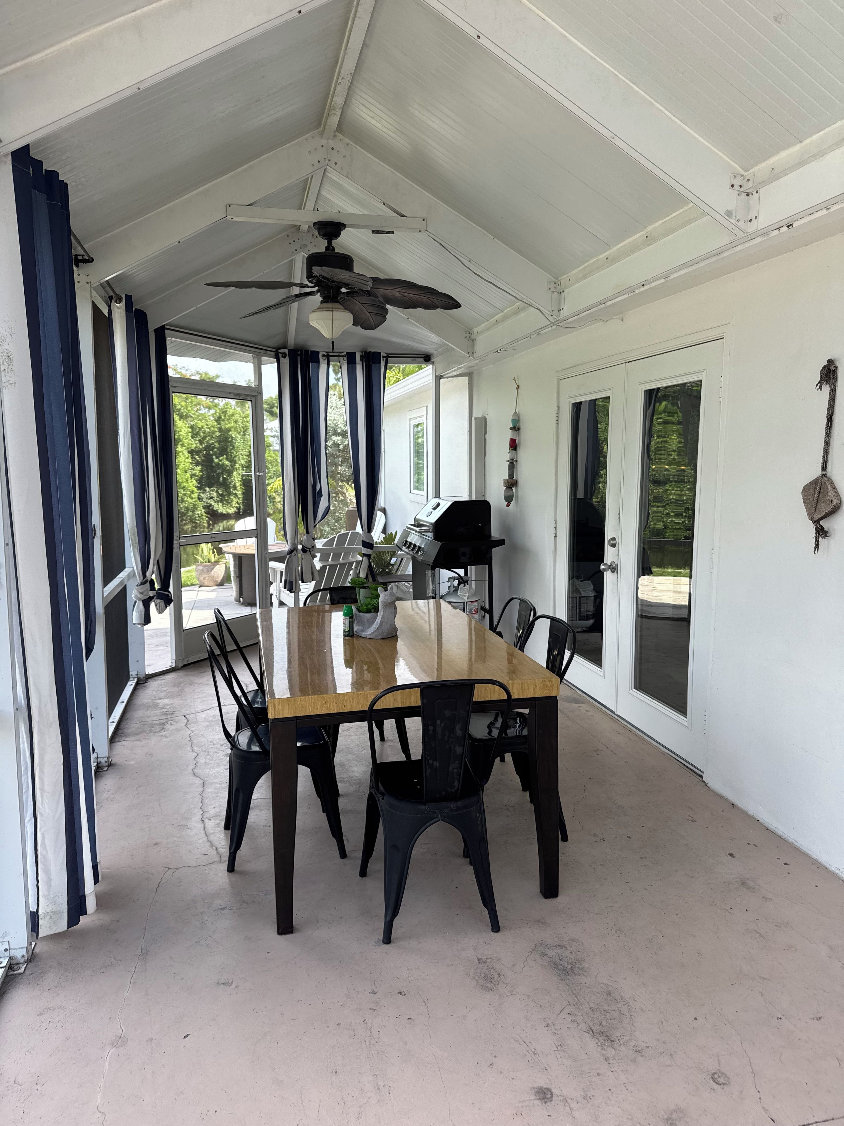 A covered patio with a dining table, chairs, and a ceiling fan.