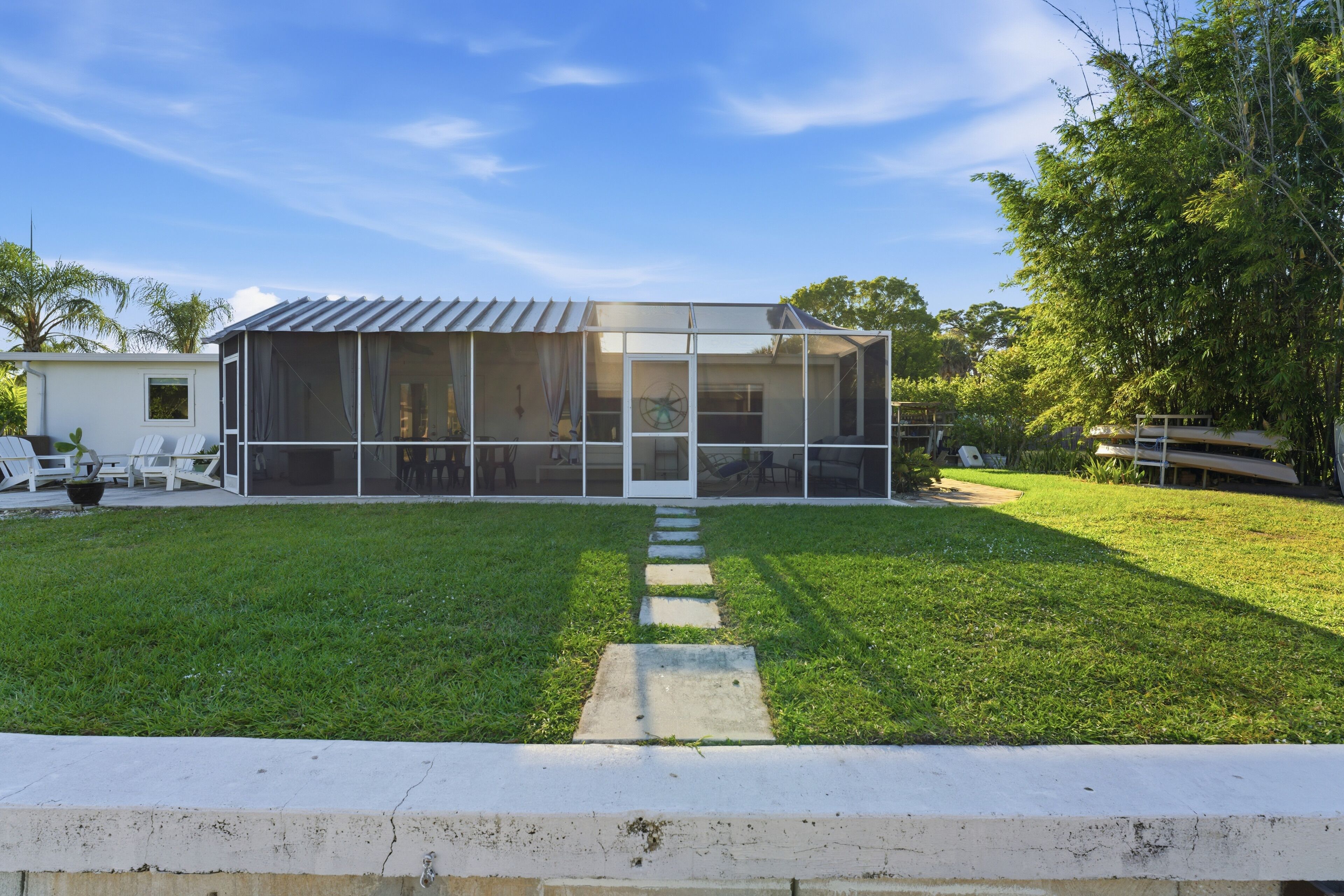 A modern house with a large glass window, a concrete pathway leading to the door, and a well-maintained lawn.