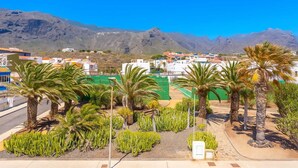 A coastal town with a view of mountains, palm trees, and a green sports field. - TenoHomes Elegant Hideaway in Nature (Puertito de los Silos)