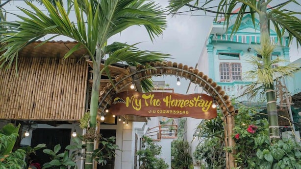 Ein Weg führt zu einem Gebäude, an dem ein Schild mit der Aufschrift "Mytho Homestay" steht.