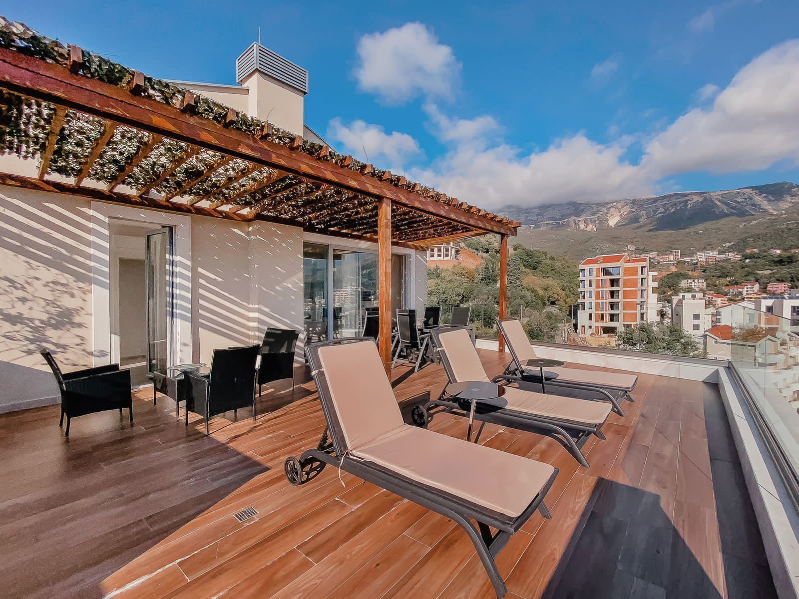 Une terrasse sur le toit avec un sol en bois, des sièges d’extérieur et une pergola.