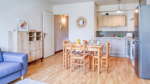 Un espace de vie compact comprenant un coin repas, une kitchenette et un canapé bleu.