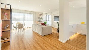 A modern living room with a sofa, dining table, and chairs. There is a kitchen area with cabinets and a countertop. - Garajau Sea Side by Atlantic Holiday (Santa Cruz)