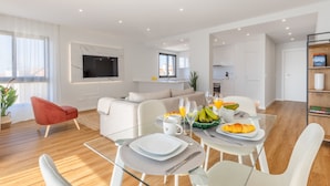 A modern living room with a dining area, white furniture, and a kitchen in the background. - Garajau Sea Side by Atlantic Holiday (Santa Cruz)