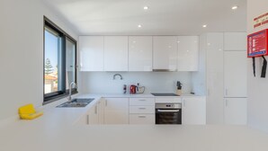 A modern kitchen with white cabinets, a stainless steel sink, and a built-in oven. - Garajau Sea Side by Atlantic Holiday (Santa Cruz)