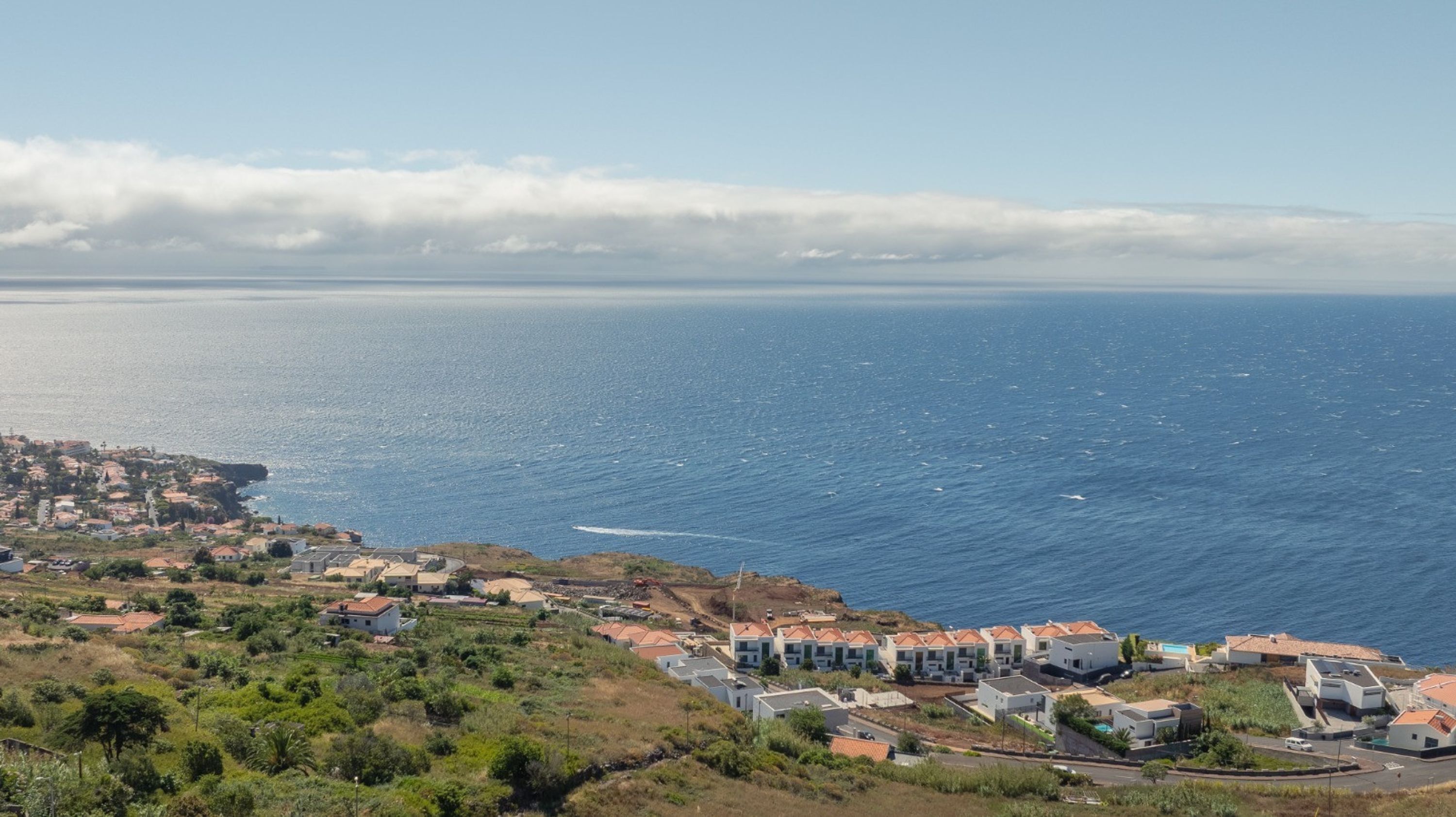 Un pueblo costero con edificios a lo largo de la costa, vista despejada del mar y un paisaje montañoso.