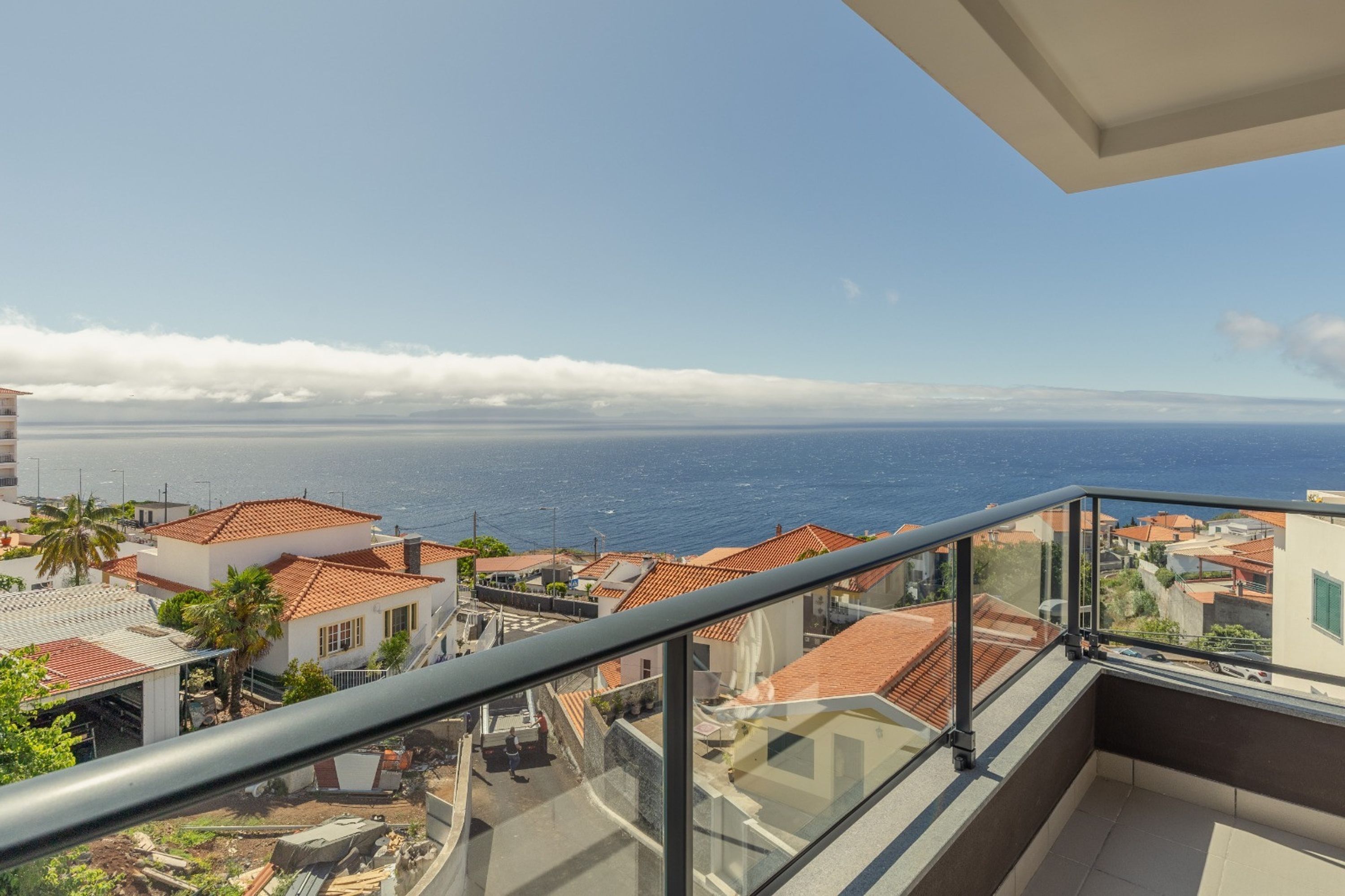 Un balcón con vistas despejadas al mar y edificios cercanos.