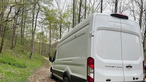 A white Transit 350HD van parked on a forest trail.