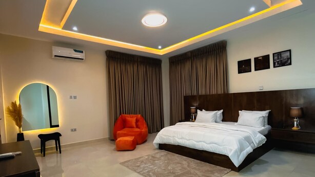 A modern bedroom with a large bed, a desk, and a chair. - Nook and Cranny Apartment (Abuja)