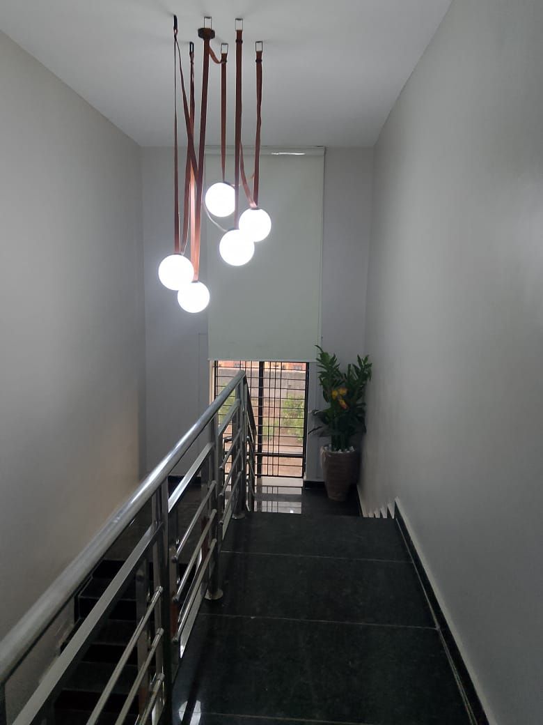 A staircase with a metal railing, a potted plant, and a ceiling light fixture.