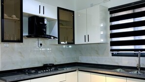 A modern kitchen with white cabinets, a black countertop, and a built-in stove. - Nook and Cranny Apartment (Abuja)