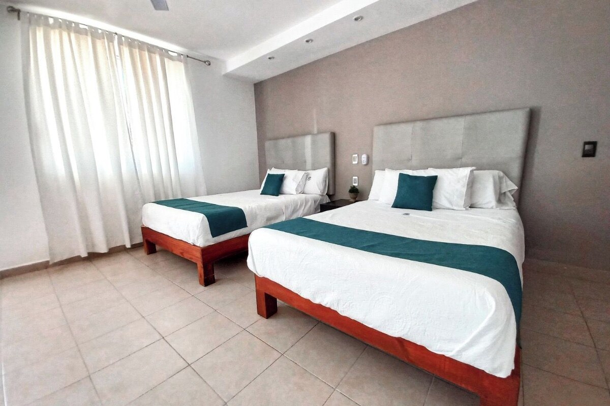 A hotel room with two beds, a large window with curtains, and a tiled floor.