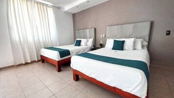 Habitación de hotel con dos camas, un ventanal grande con cortinas y suelo de baldosas.