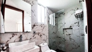 Un baño con lavamanos, inodoro y ducha de mármol.