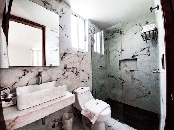 Un baño con lavamanos, inodoro y ducha de mármol.